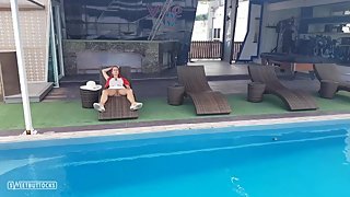 Girl with red hair sunbathes without panties by the pool